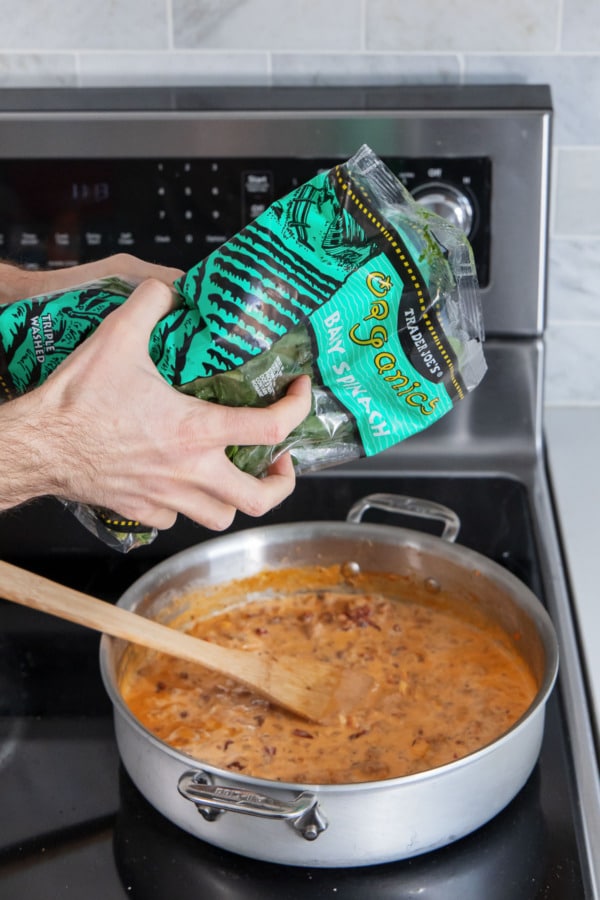 Crushing a bag of frozen spinach between your hands to break up the leaves.