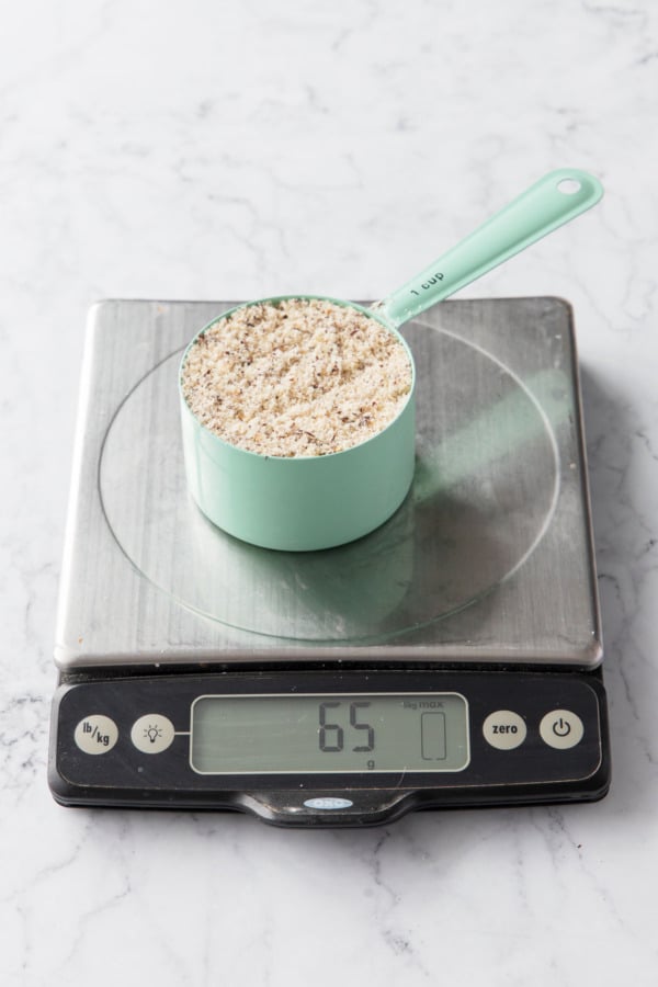 Half cup of hazelnut flour on a scale showing a weight of 65 grams.