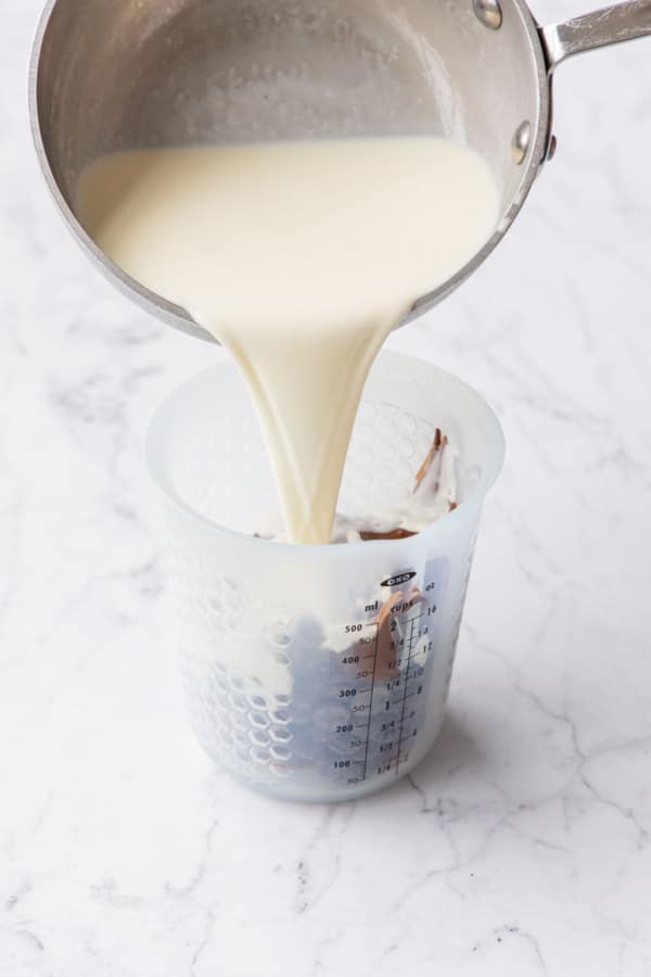 Pouring hot cream into a tall container with chocolate and nutella.