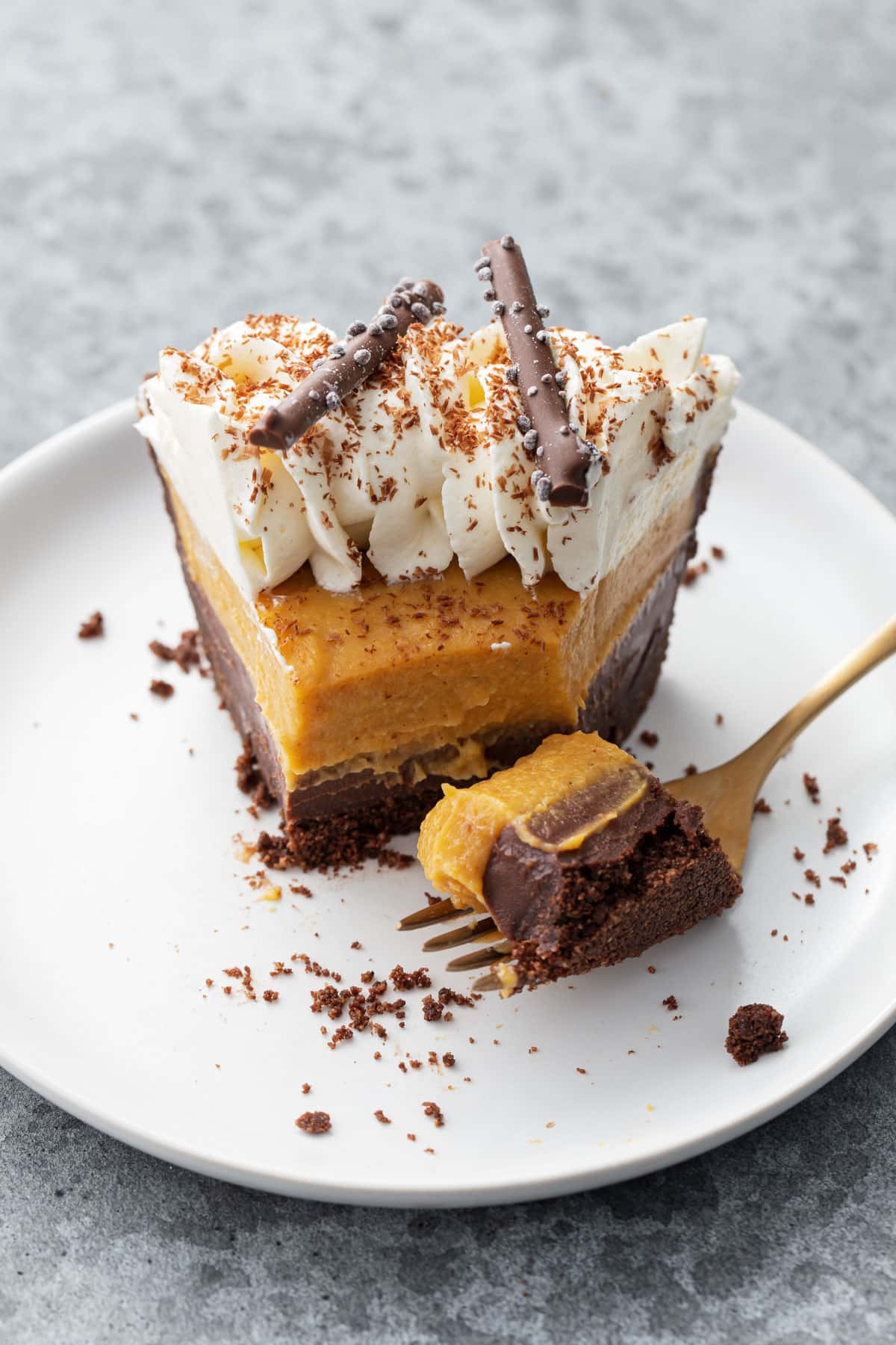 Closeup, slice of Black Bottom Pumpkin Cream Pie with a bite taken out of the tip and sitting on a gold fork.