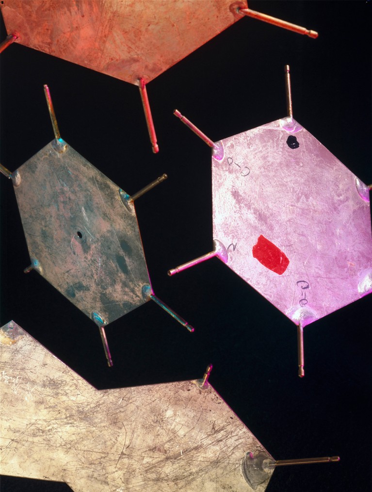 Orange, beige, grey and pink aluminium templates floating on a black background, are part of a model representing the structure of DNA. The plates represent bases, those groups of atoms that make up DNA's twin strands.